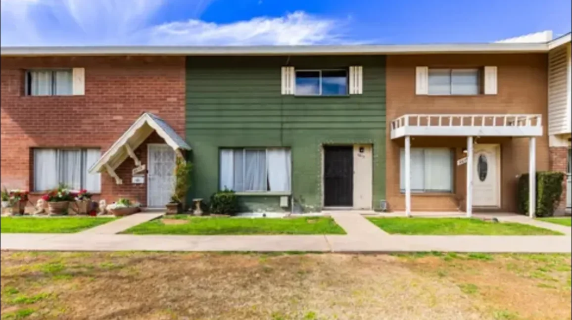 A row of brick and painted townhomes with front lawns and walkways