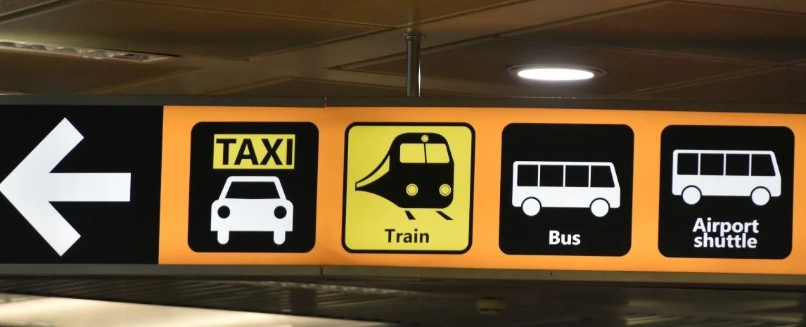 Overhead signage pointing to taxi, train, bus and shuttle connections